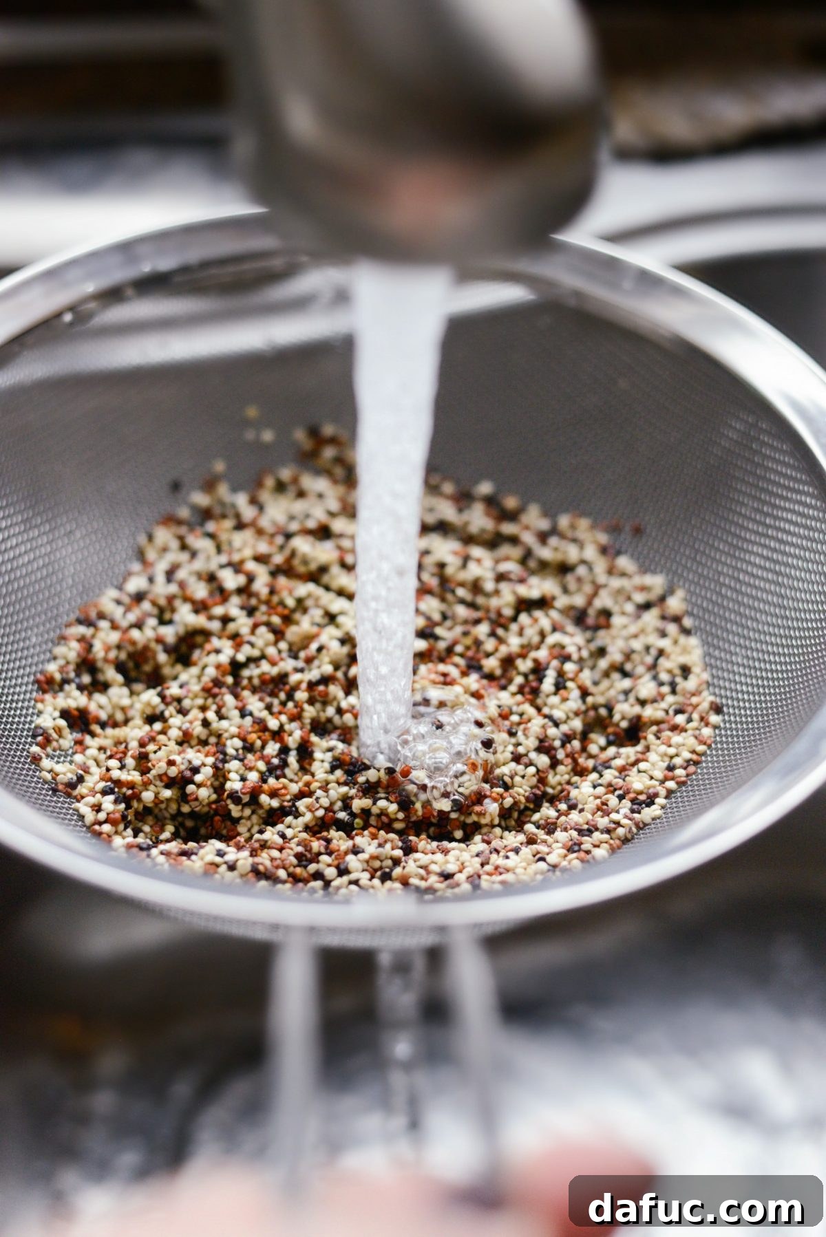 Rinsing quinoa under running water in a mesh strainer