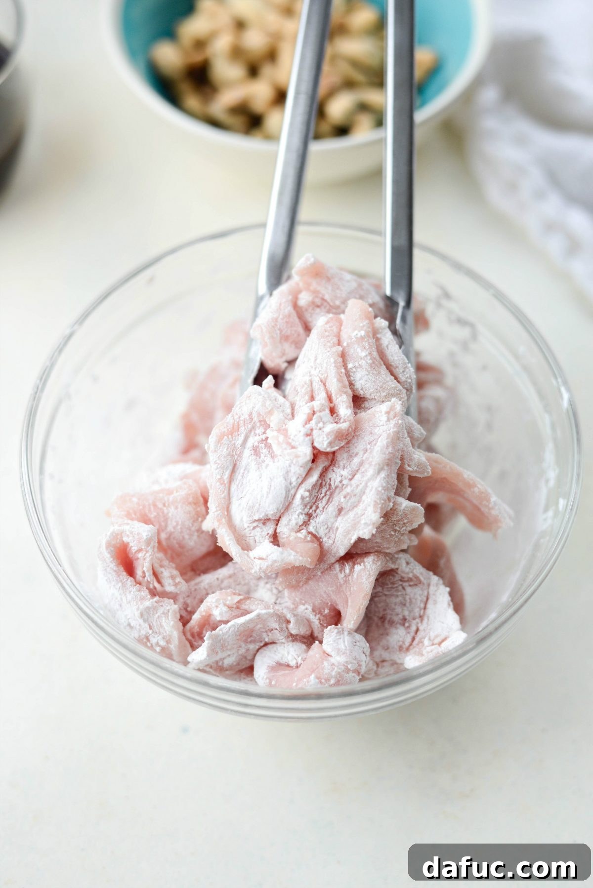 Tossing thinly sliced pork pieces with cornstarch and white pepper