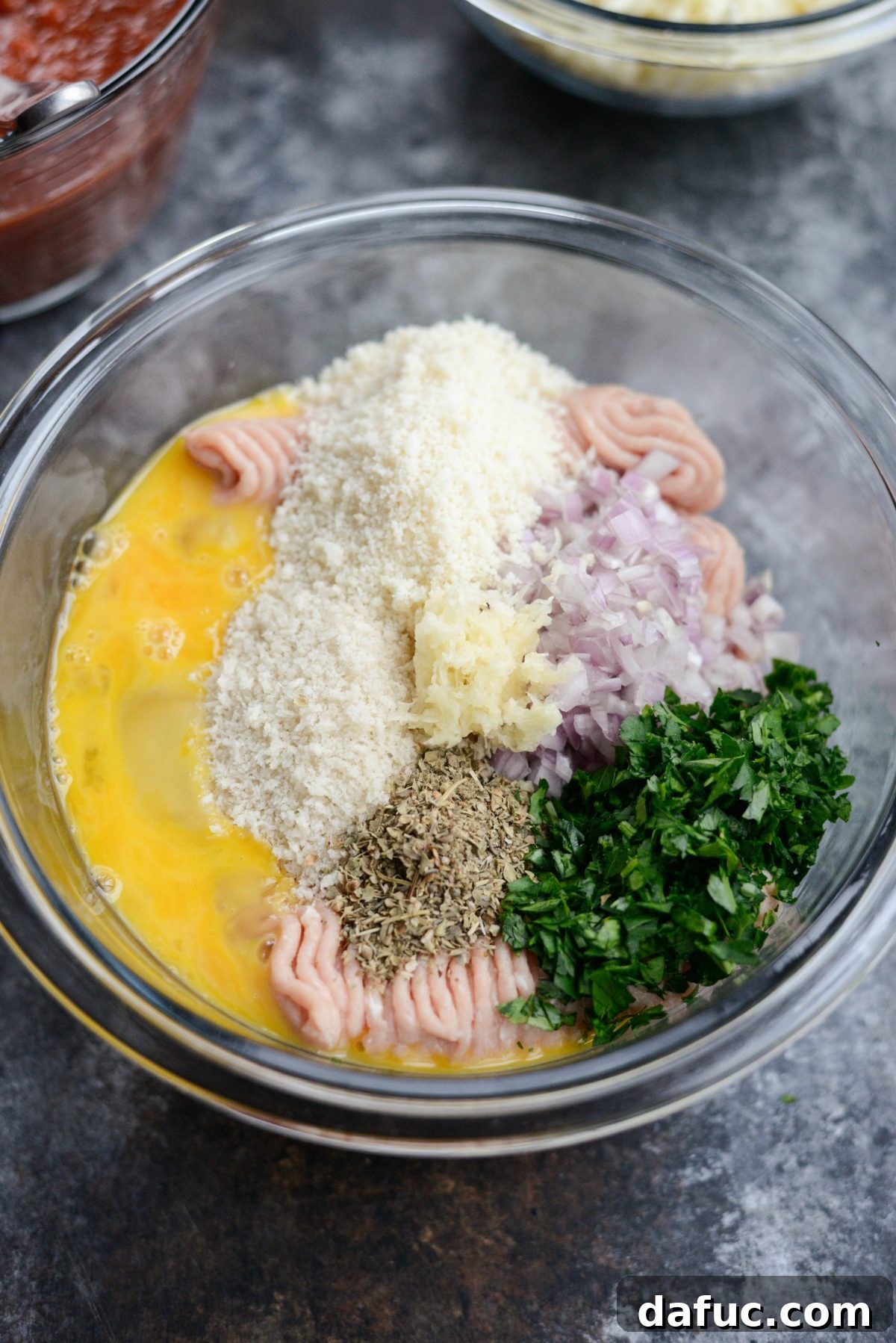 Chicken Parm Skillet Meatballs 6 A large bowl containing all the raw ingredients for the chicken parmesan meatballs: ground chicken, breadcrumbs, cheese, and herbs.