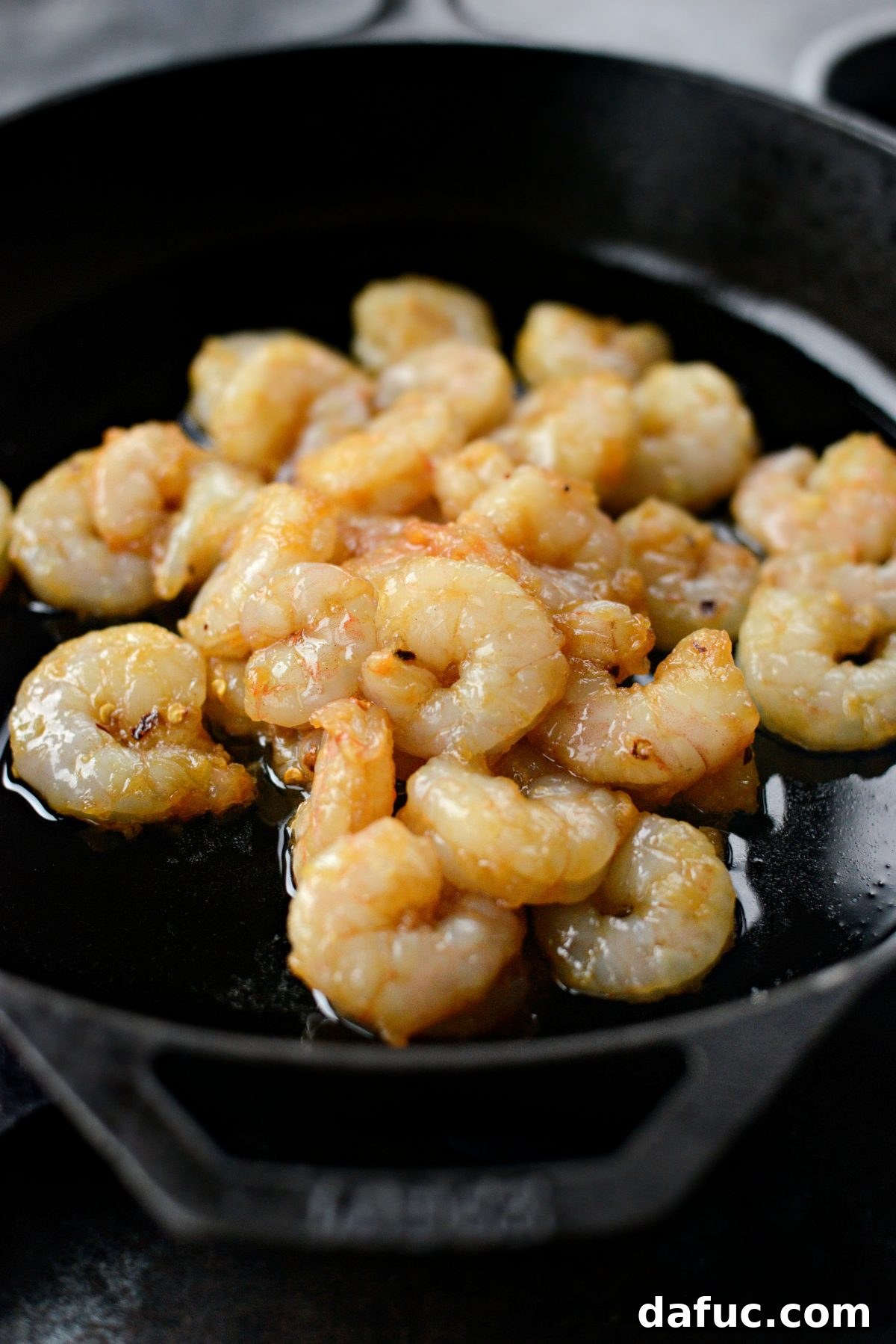 Adding shrimp in an even layer to a hot skillet with oil