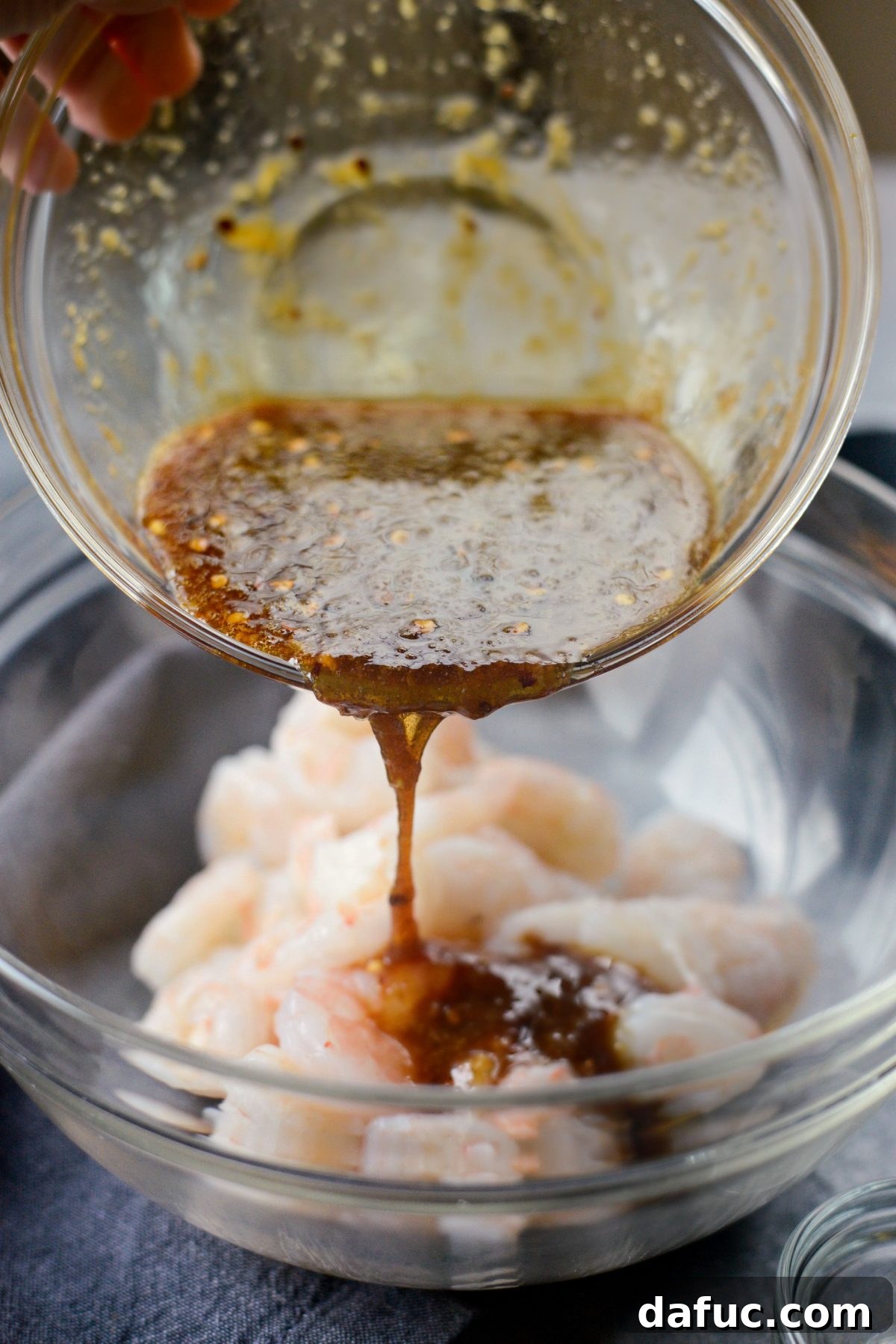 Pouring a third of the honey garlic sauce over shrimp