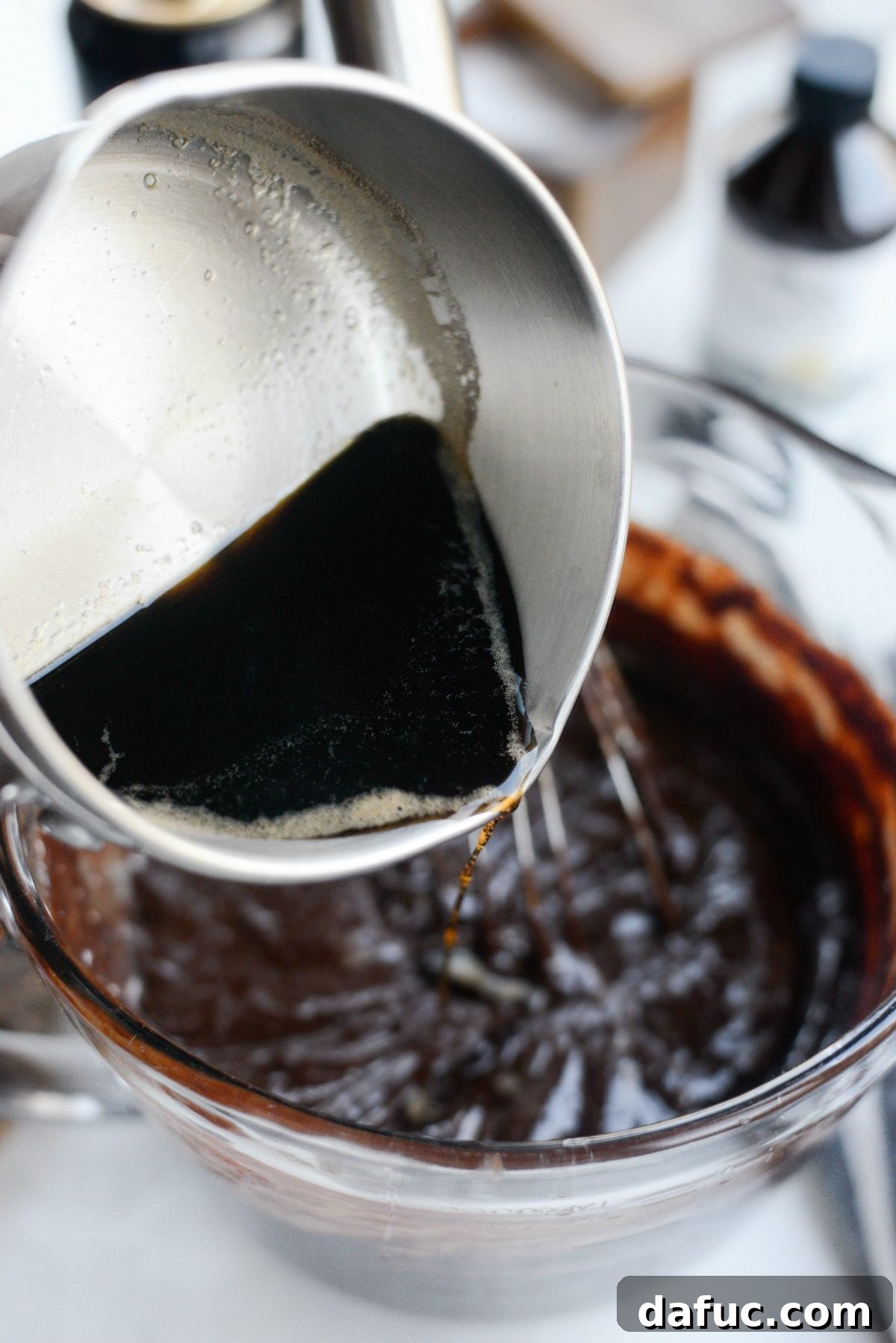 Reduced Guinness beer being added to the chocolate and egg mixture in a bowl