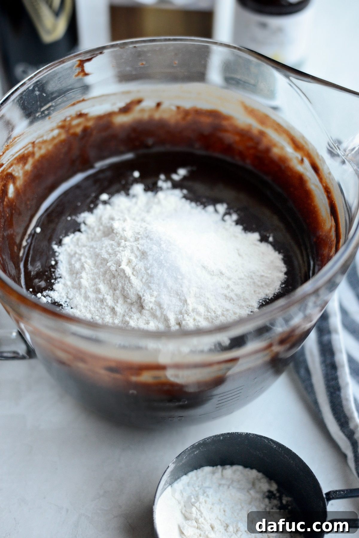 All-purpose flour and kosher salt being added to the wet brownie batter