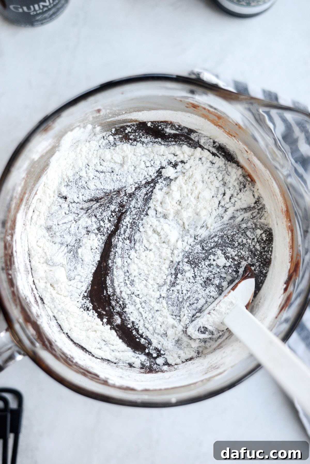 Rubber spatula gently stirring flour and salt into the brownie batter until just combined