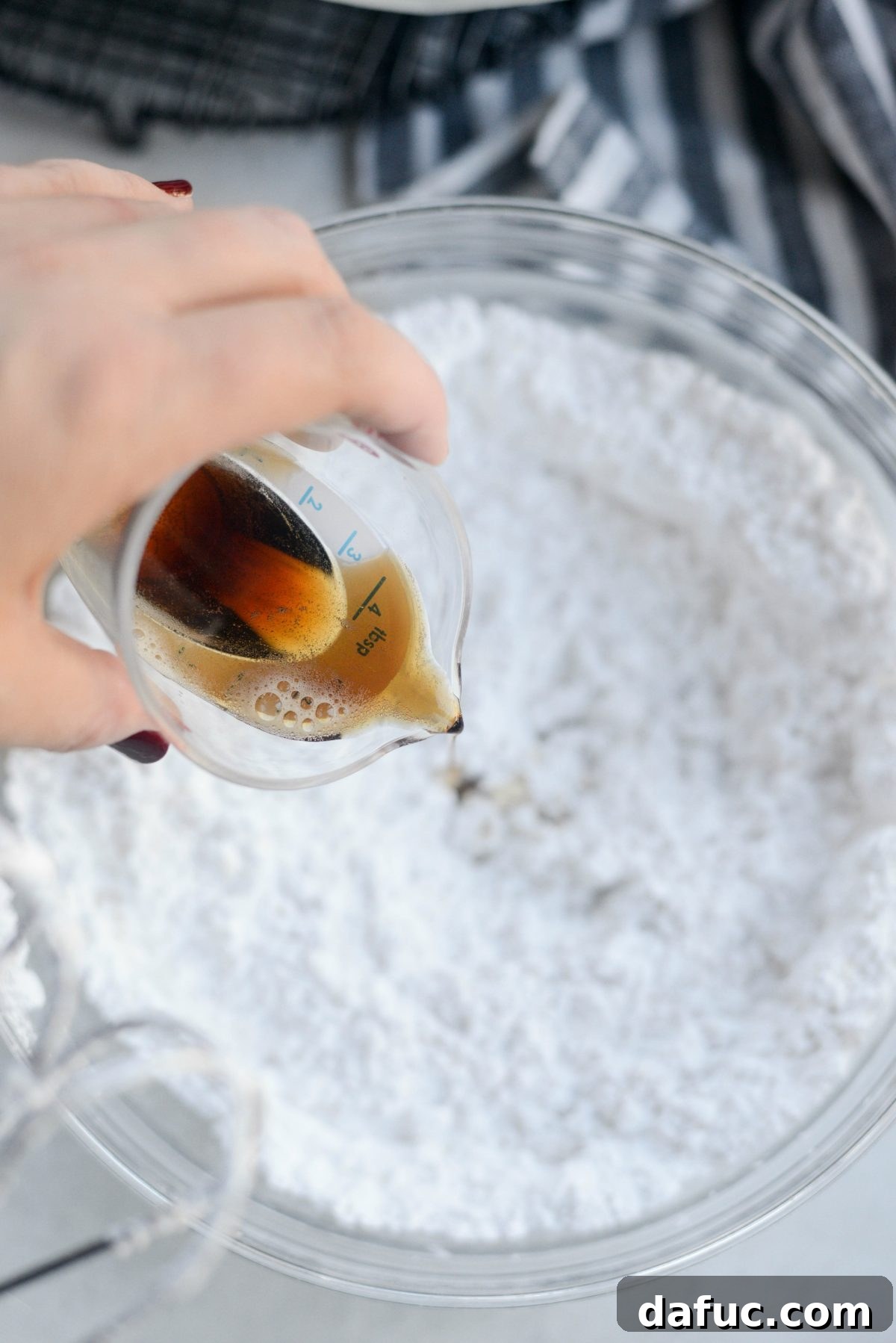 Two tablespoons of Guinness beer being added to the brown butter and powdered sugar mixture