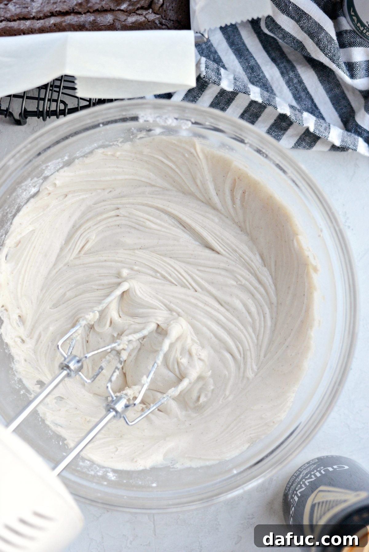 Electric mixer blending all frosting ingredients until a smooth, creamy consistency is achieved