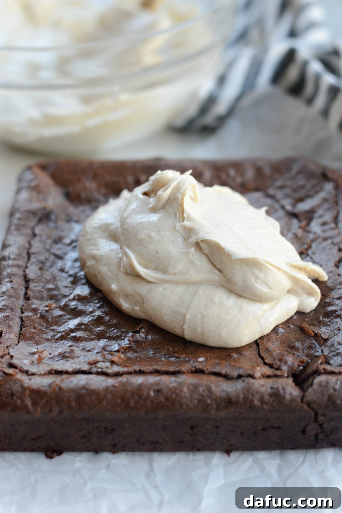 Brown butter stout frosting being generously spread over the cooled Chocolate Guinness Brownies