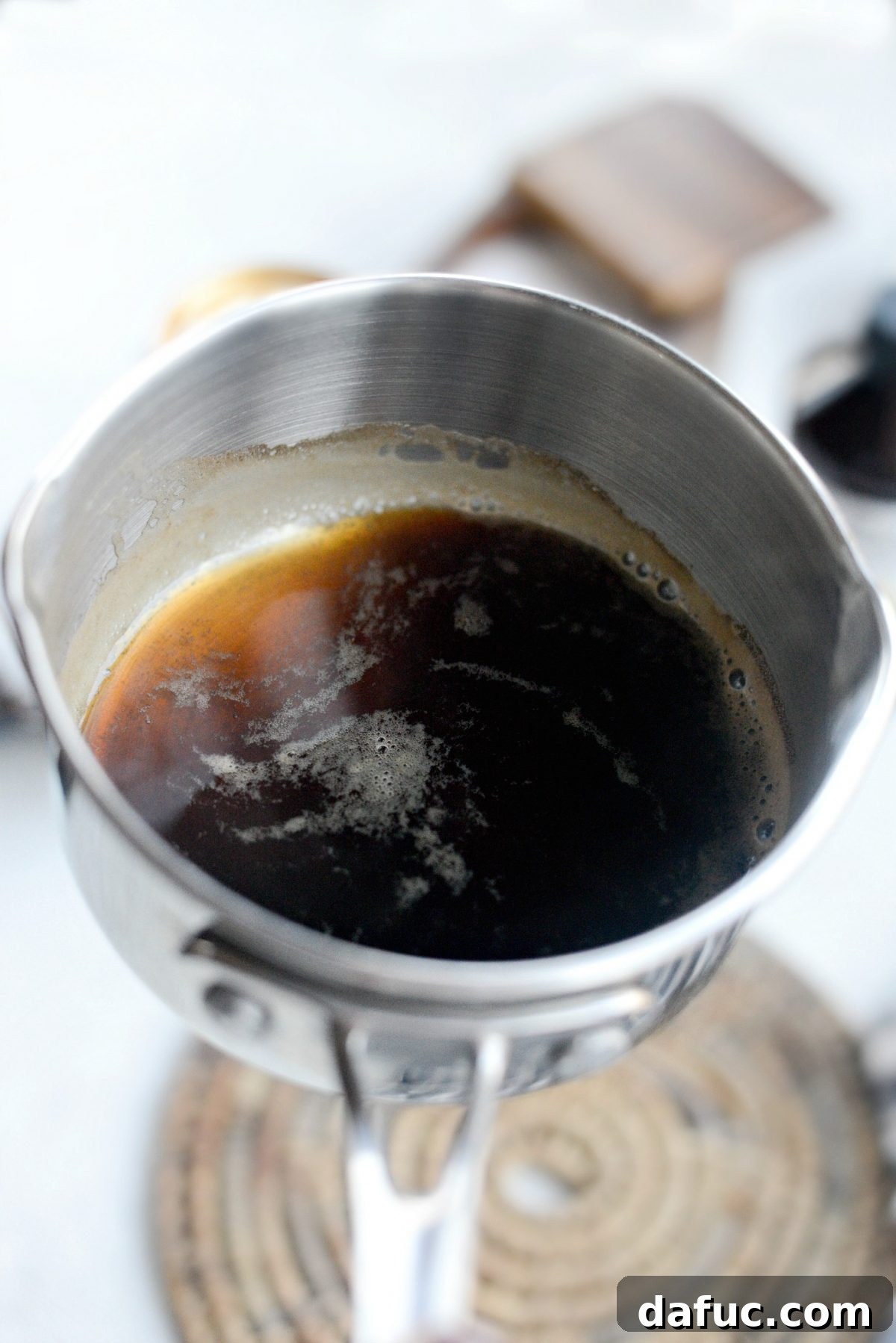 Guinness beer simmering in a small saucepan, reducing to concentrate its flavor for brownies