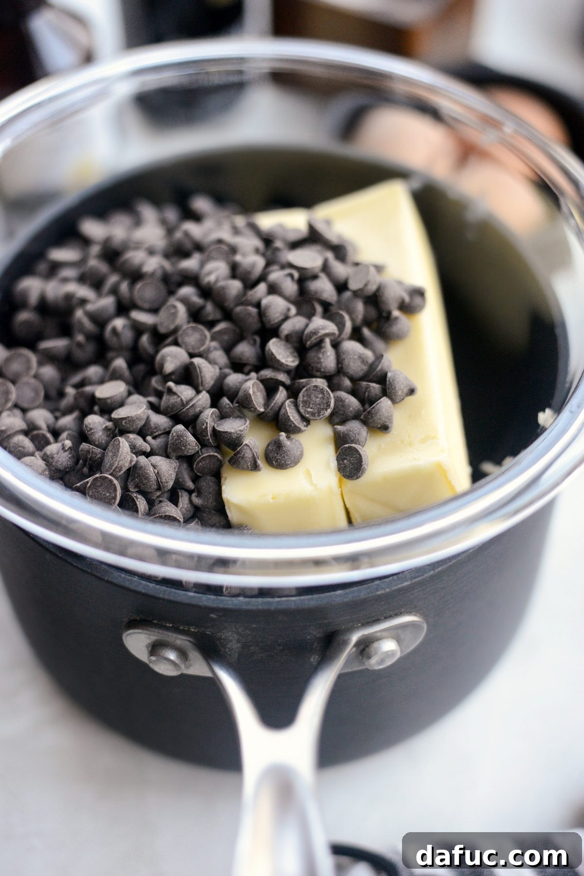 Unsalted butter and bittersweet chocolate melting together in a mixing bowl over simmering water