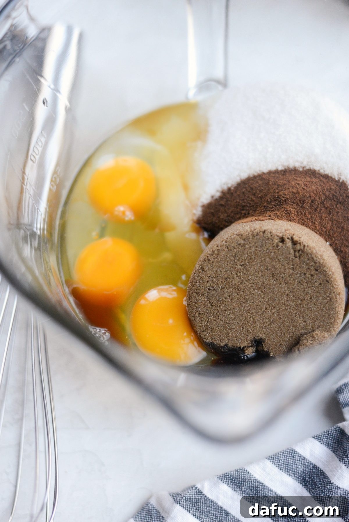 Large mixing bowl containing eggs, vanilla extract, granulated sugar, dark brown sugar, and instant espresso powder