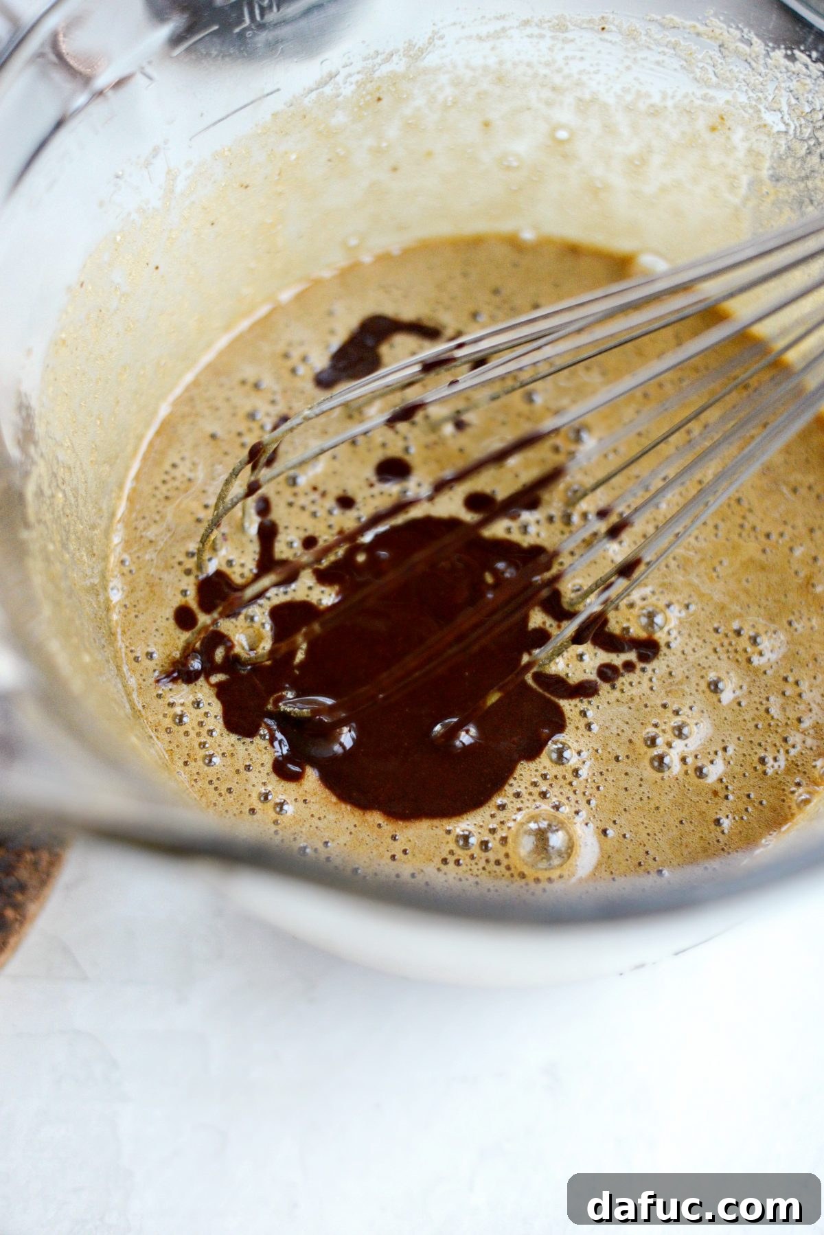 Cooled chocolate and butter mixture being poured into the egg and sugar mixture