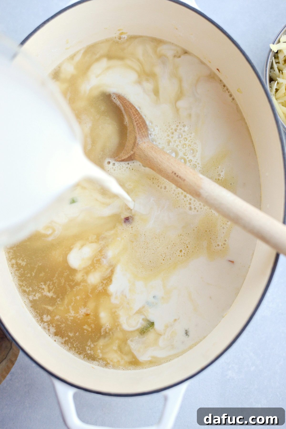 Half & half being added to the soup base, ready to be stirred and simmered for a creamy texture.