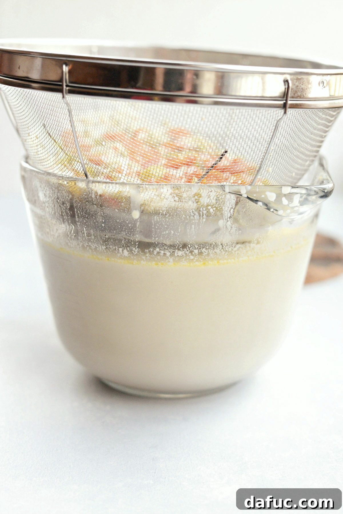 Straining the soup through a fine mesh strainer into a large bowl to achieve a smooth consistency.
