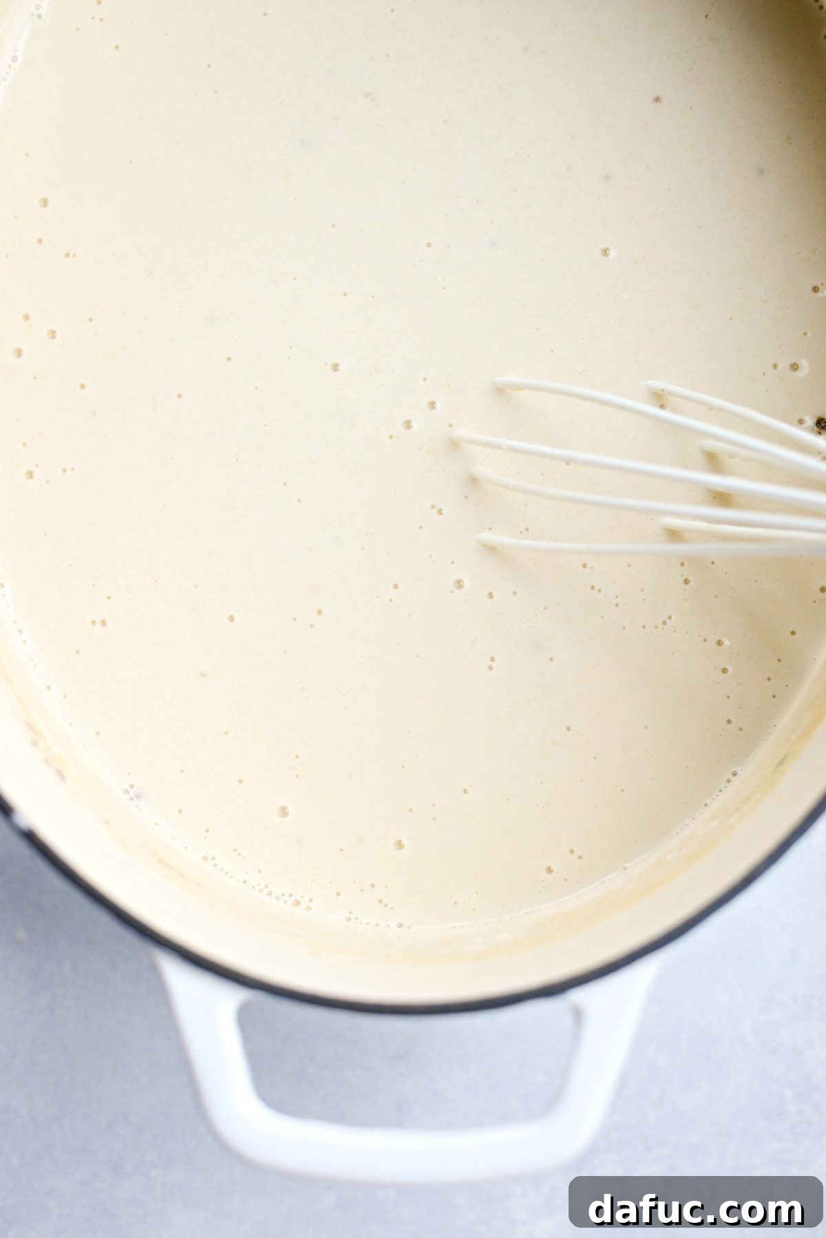 Stirring the Irish white cheddar cheese into the soup until fully melted and creamy.