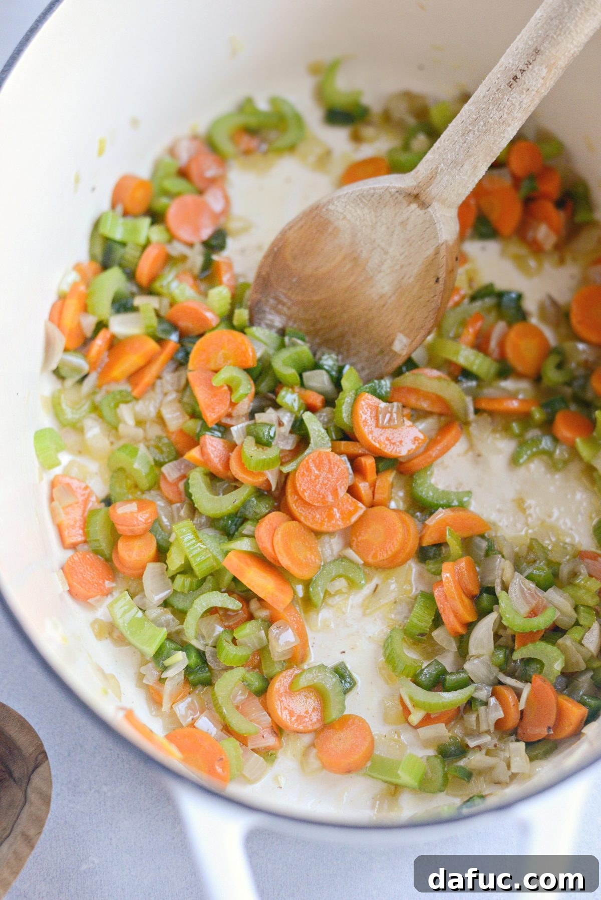 Sautéing diced shallots, carrots, celery, and jalapeño in rendered bacon fat in a Dutch oven.