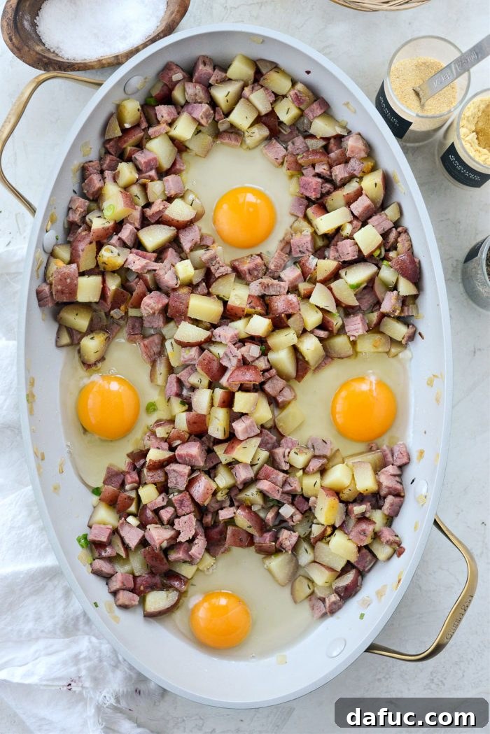 Skillet of corned beef hash with eggs baking in the oven at 375 degrees Fahrenheit.