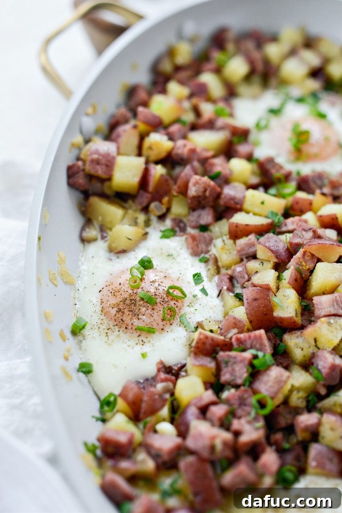 A generous serving of corned beef hash with a perfectly baked egg, scooped onto a plate.