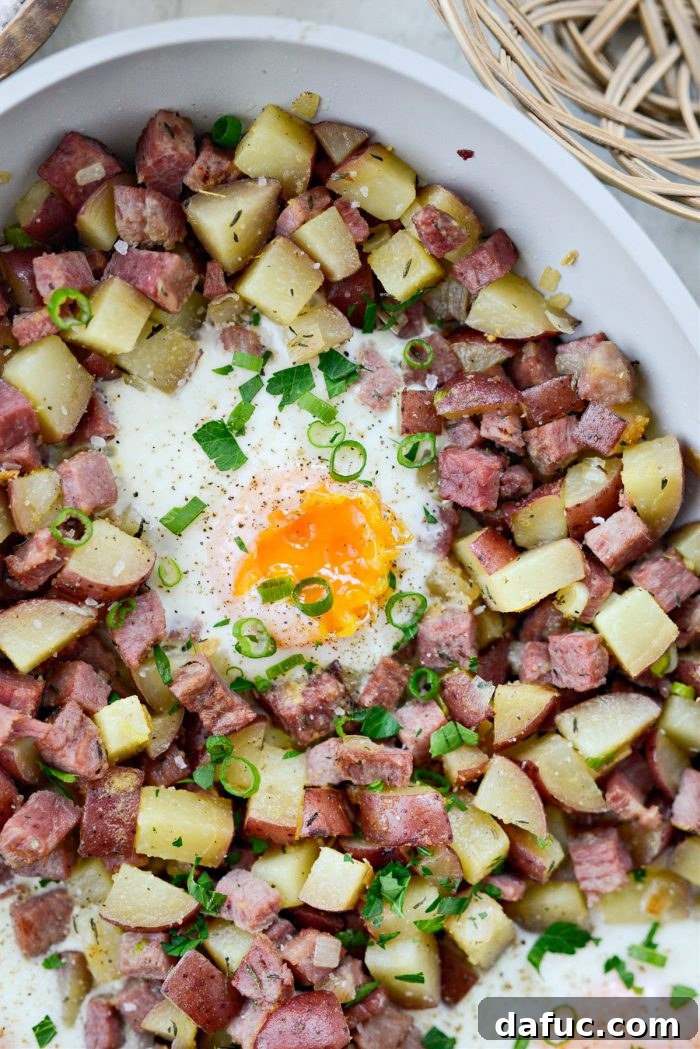 Another enticing angle of the corned beef hash with eggs, showcasing the hearty texture and fresh garnishes.