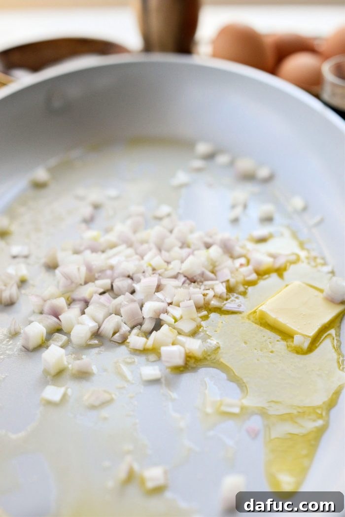 Minced shallots being sautéed in melted butter and olive oil until translucent and tender.