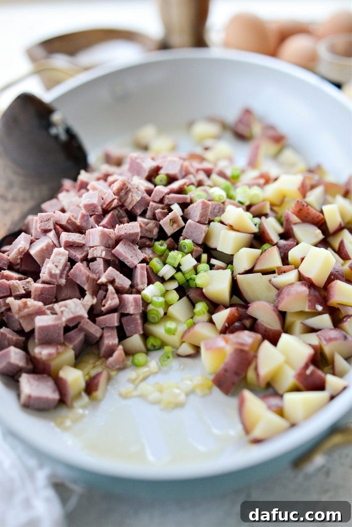 Diced potatoes, corned beef, and the light green parts of green onions added to the skillet with sautéed shallots.
