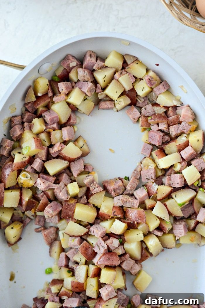 Four distinct wells made in the corned beef hash mixture, ready for eggs.