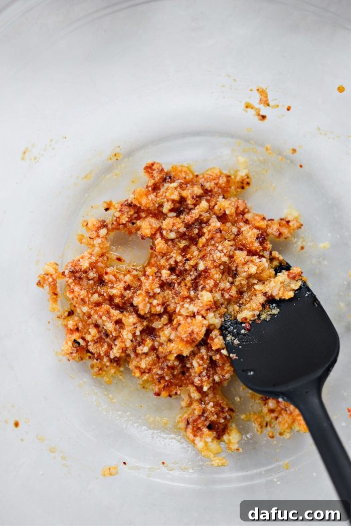 Stirring the chili crunch, Parmesan, and lemon mixture