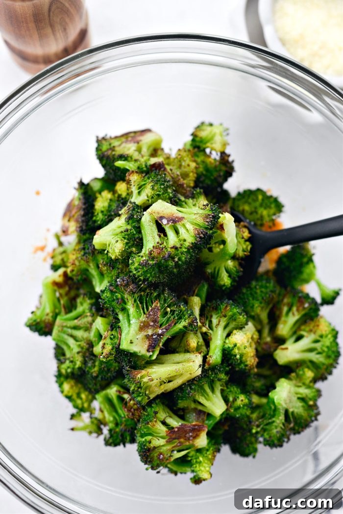 Adding roasted broccoli to the bowl with chili crunch and Parmesan