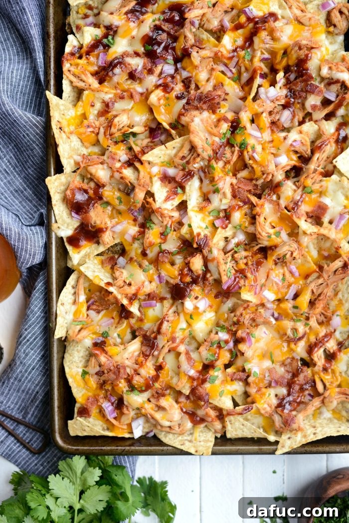 Sheet Pan BBQ Chicken Nachos served on a rustic wooden board.