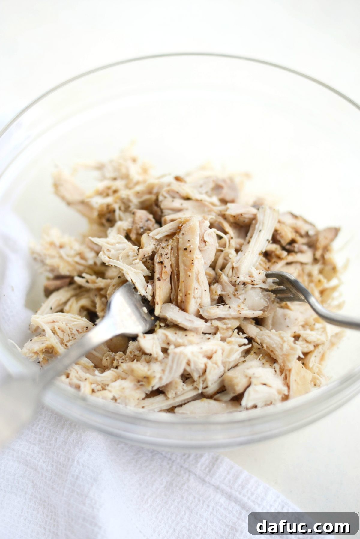 Shredding cooked chicken with two forks for BBQ nachos.