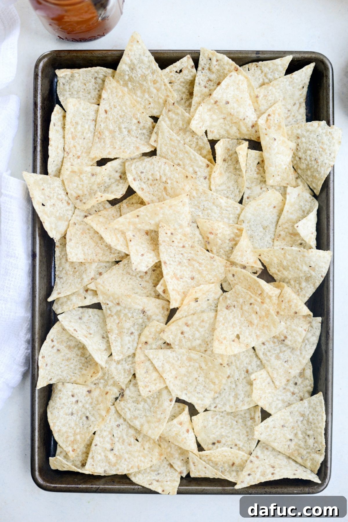 First layer of tortilla chips on a baking sheet.