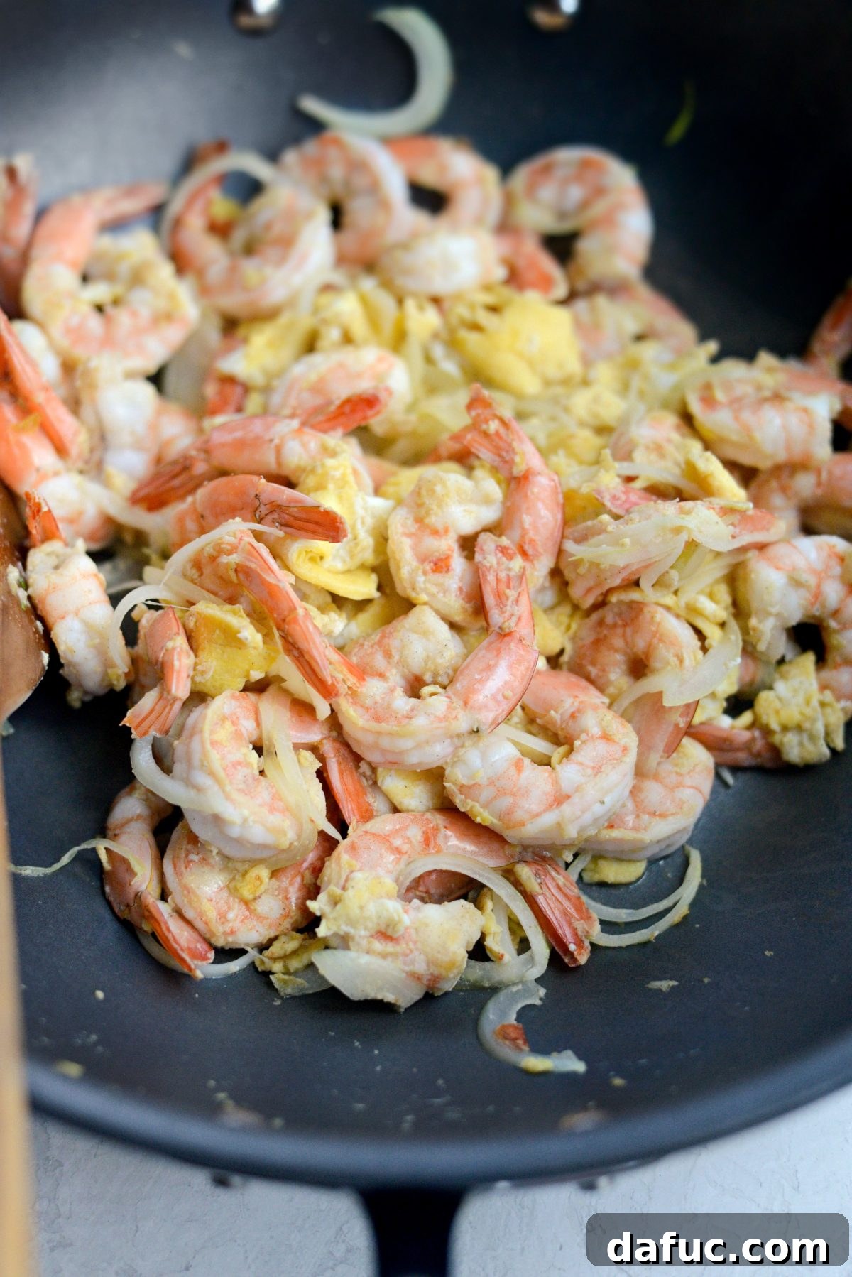 Cooked eggs with shrimp and onions in a wok