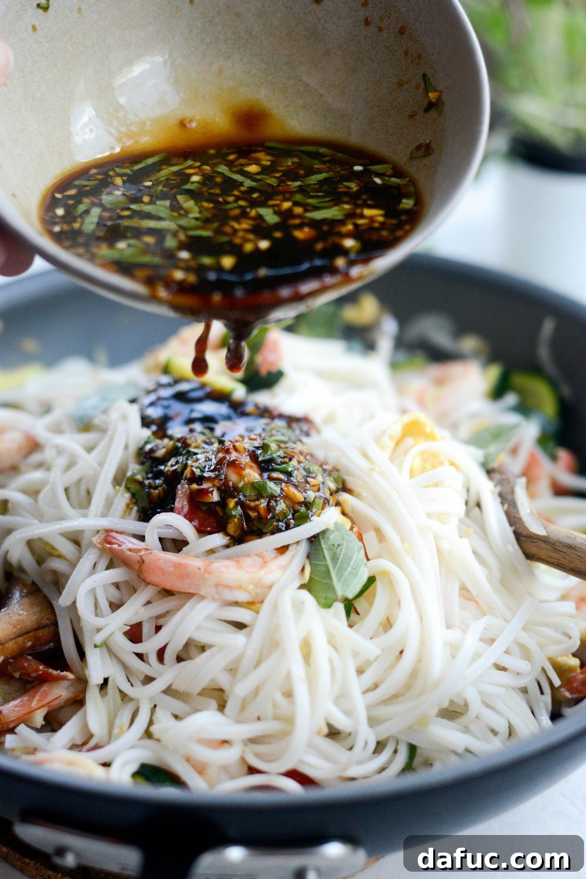 Pouring Drunken Noodles sauce into the skillet