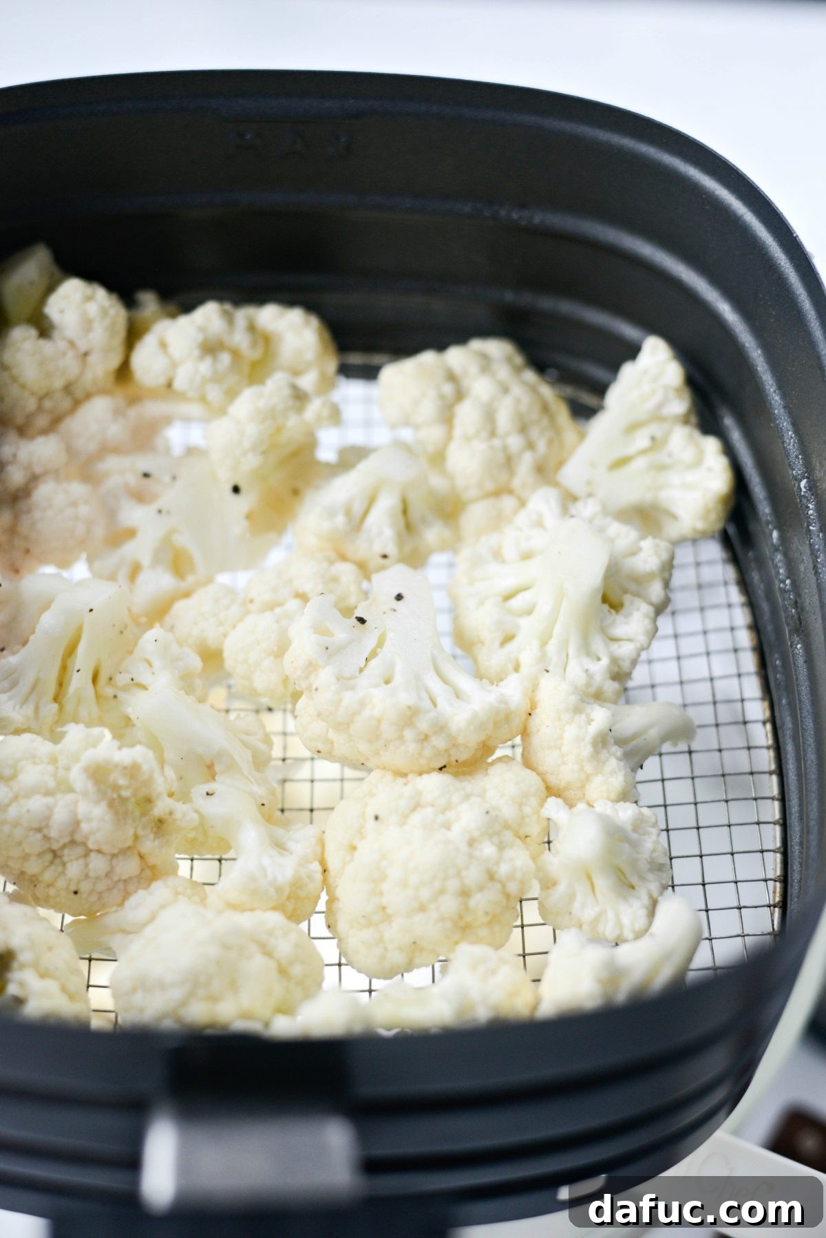 First batch of cauliflower florets in the air fryer basket
