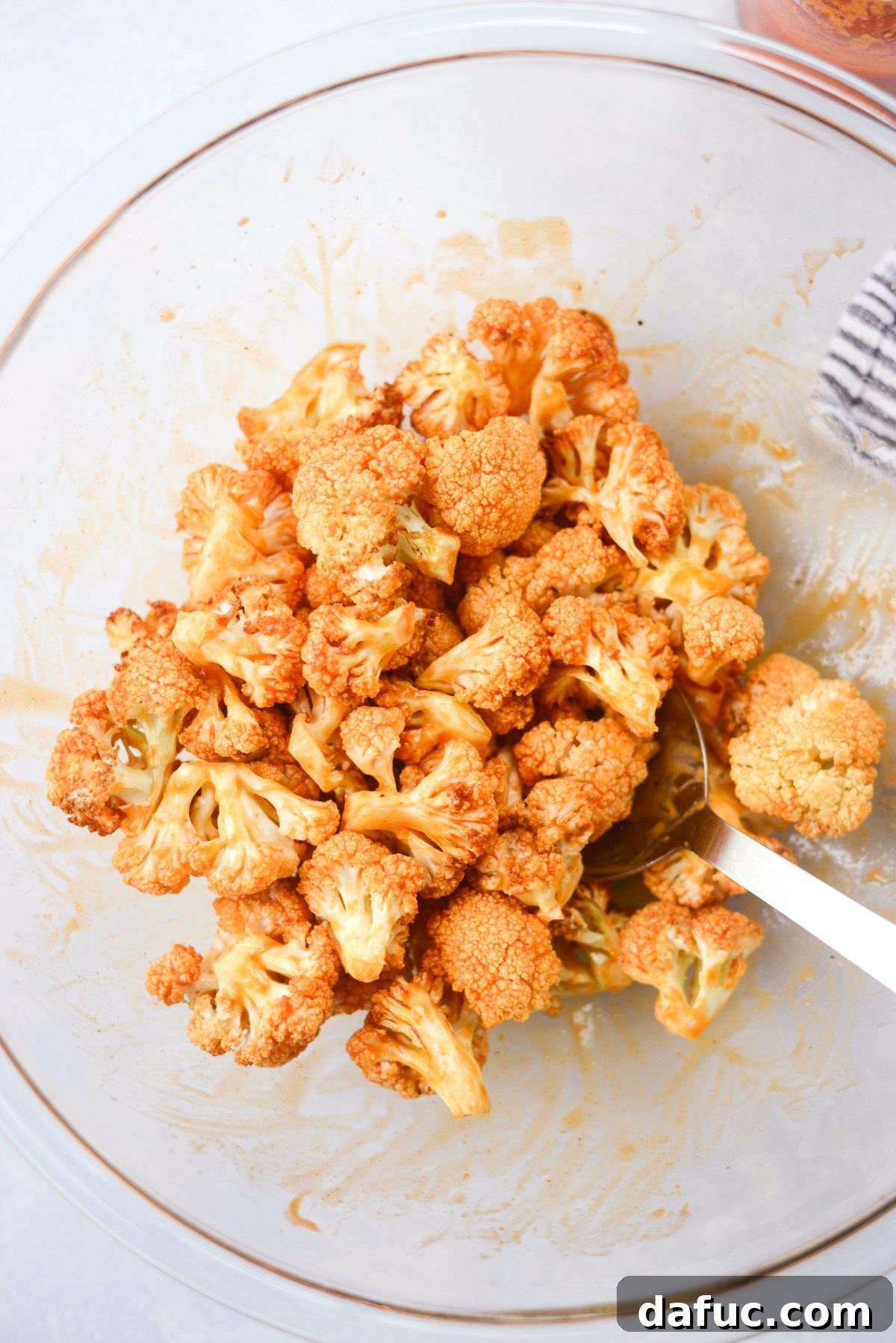 Tossing cauliflower bites in buffalo sauce