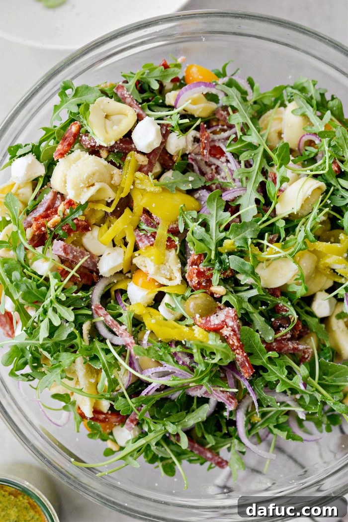 Baby arugula being added to the mixing bowl with other salad ingredients