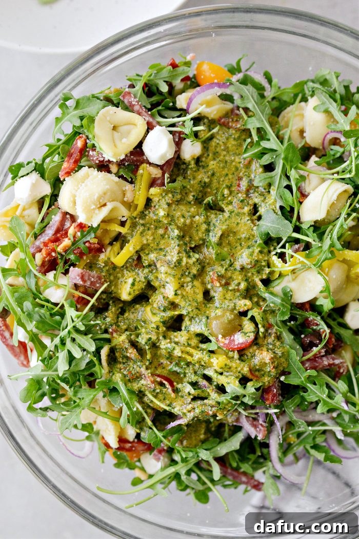 Basil pesto vinaigrette being drizzled over the pasta salad ingredients