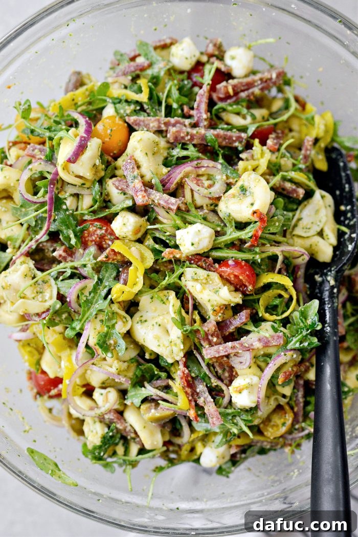 Italian Tortellini Pasta Salad being tossed to coat with dressing