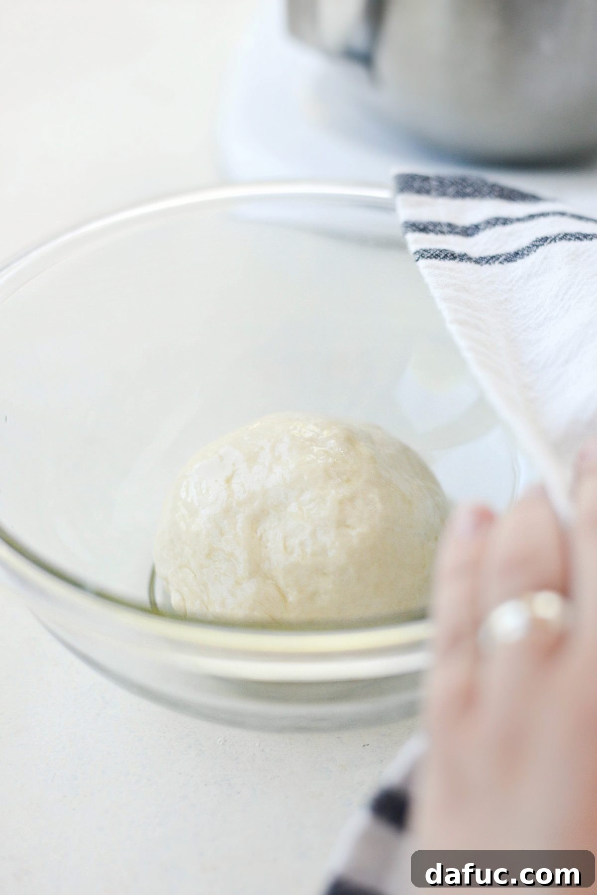 Mastering Homemade Pizza Dough 11 Pizza dough rising in an oiled bowl covered with a towel