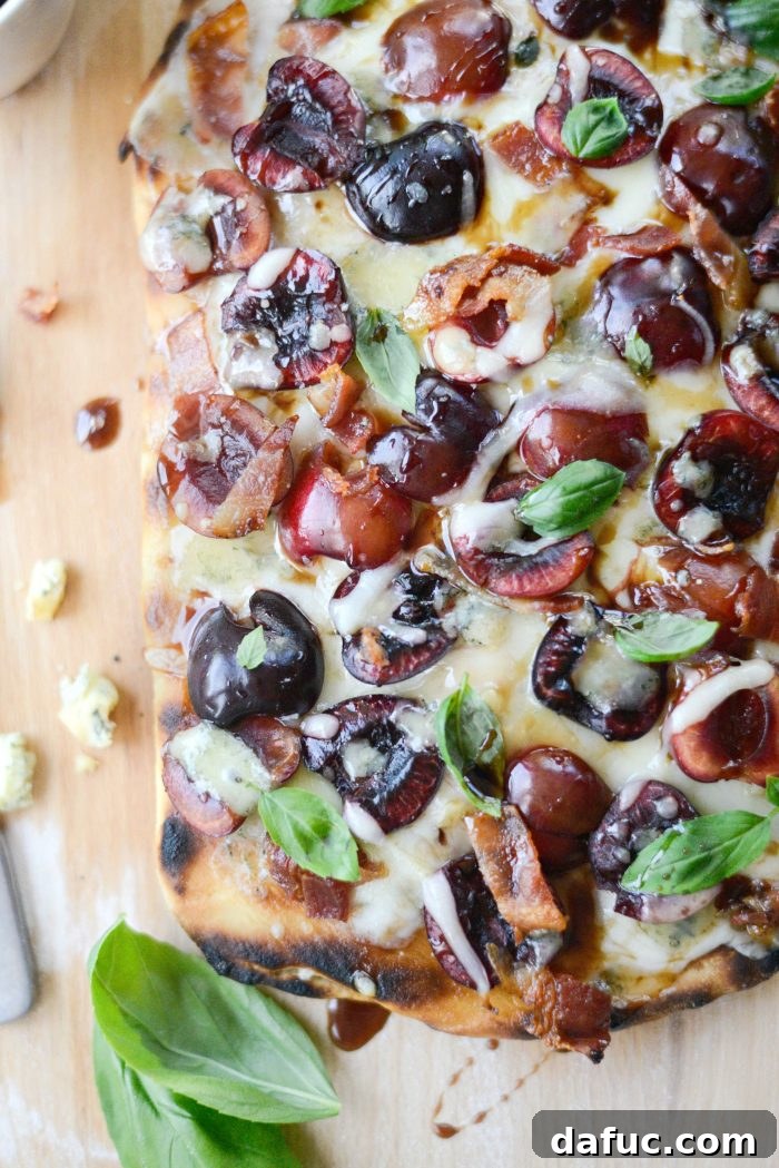 A whole Grilled Cherry Gorgonzola Flatbread Pizza on a wooden board