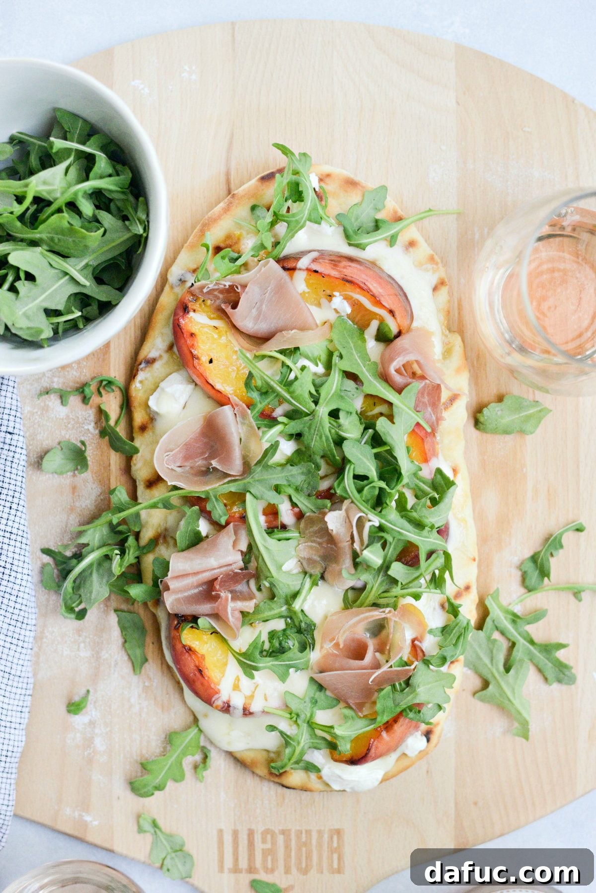 Grilled flatbread topped with fresh prosciutto ribbons and vibrant arugula