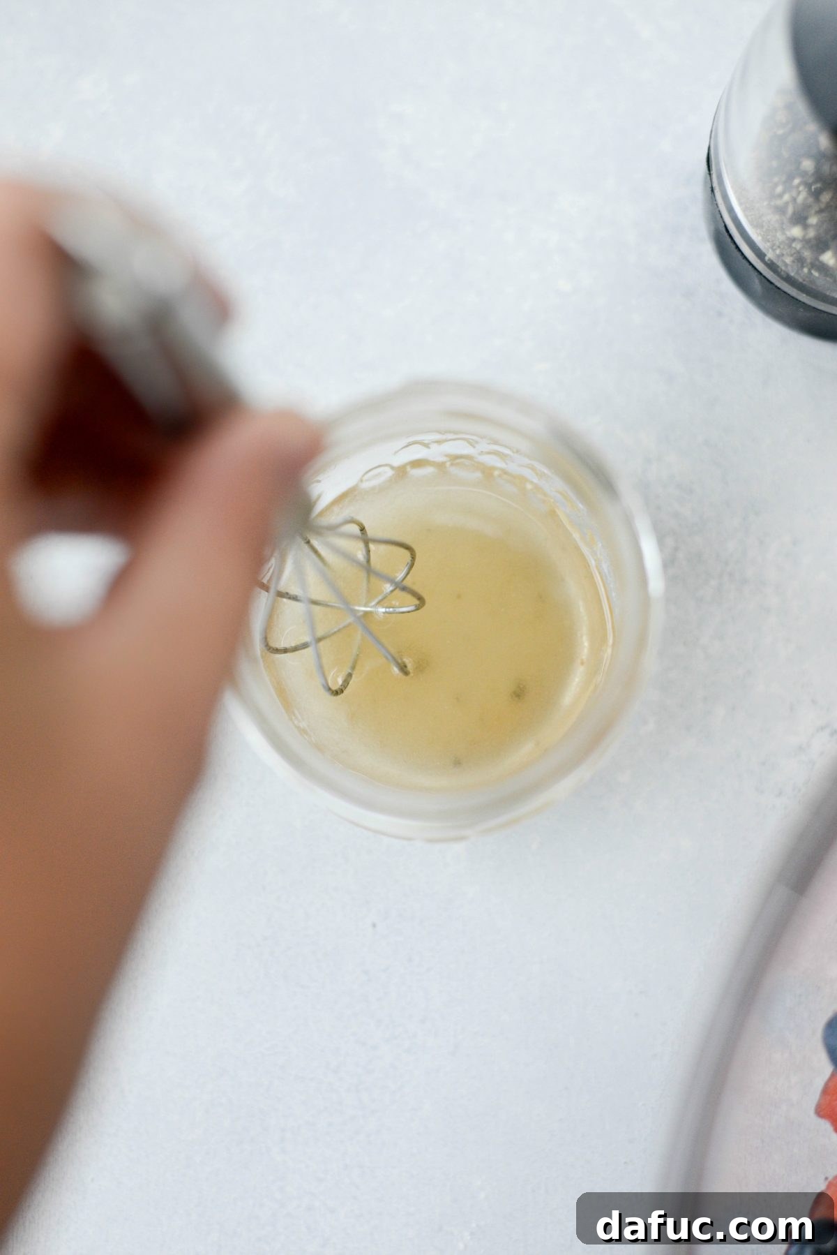 Making champagne vinaigrette in a small jar with olive oil, vinegar, salt, and pepper.