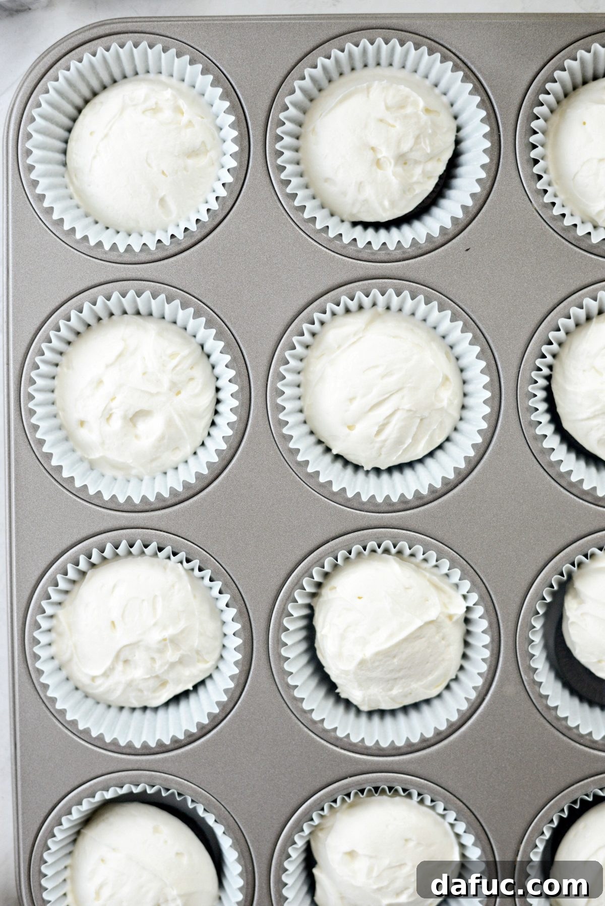 Decadent No-Bake Cookies and Cream Cheesecake Bites 13 The muffin pan being firmly tapped on a hard surface to settle the cheesecake filling