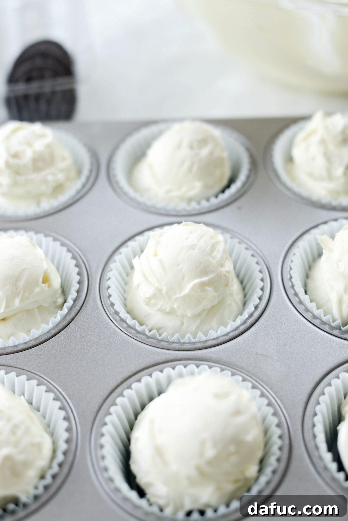 Adding a second dollop of cheesecake filling to each mini cheesecake