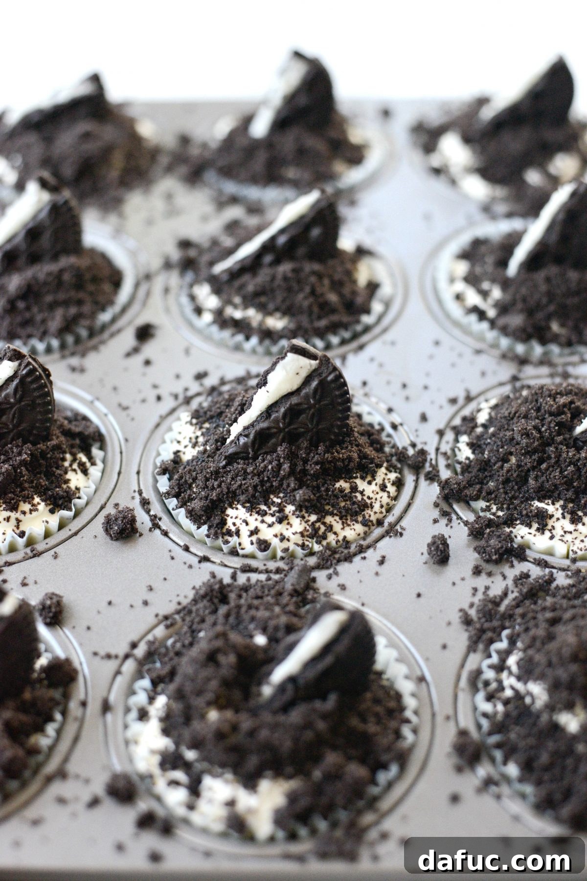 Decadent No-Bake Cookies and Cream Cheesecake Bites 3 Close-up view of three No-Bake Cookies and Cream Mini Cheesecakes, highlighting their creamy filling and crushed cookie topping