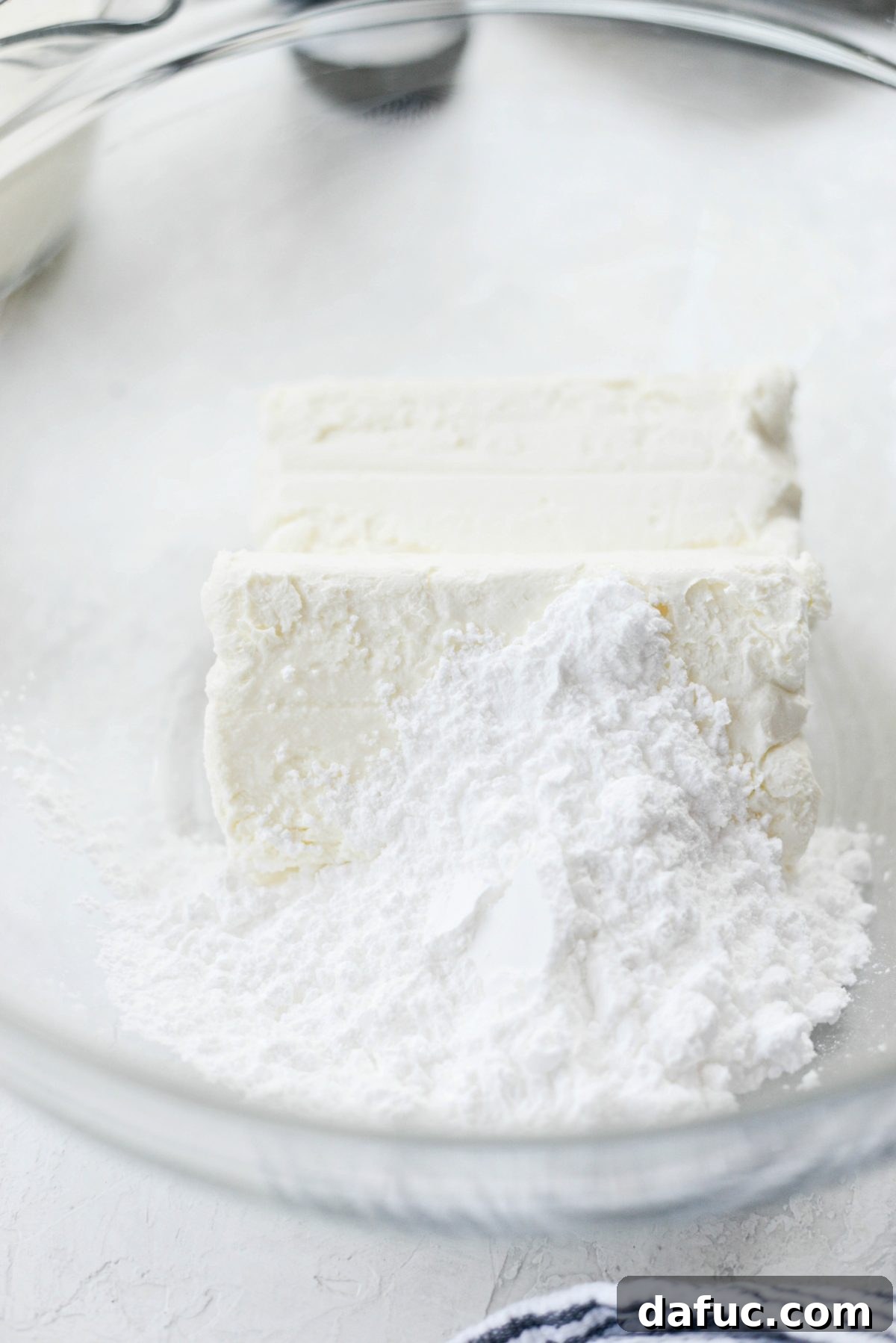 Decadent No-Bake Cookies and Cream Cheesecake Bites 5 Softened cream cheese and sifted powdered sugar in a mixing bowl, ready to be blended for the cheesecake filling