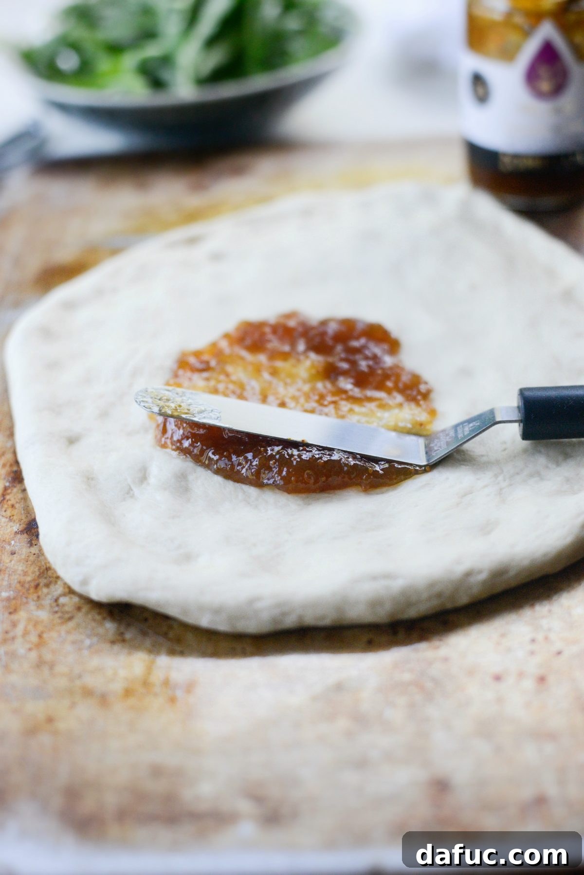 Spreading fig jam evenly on pizza crust