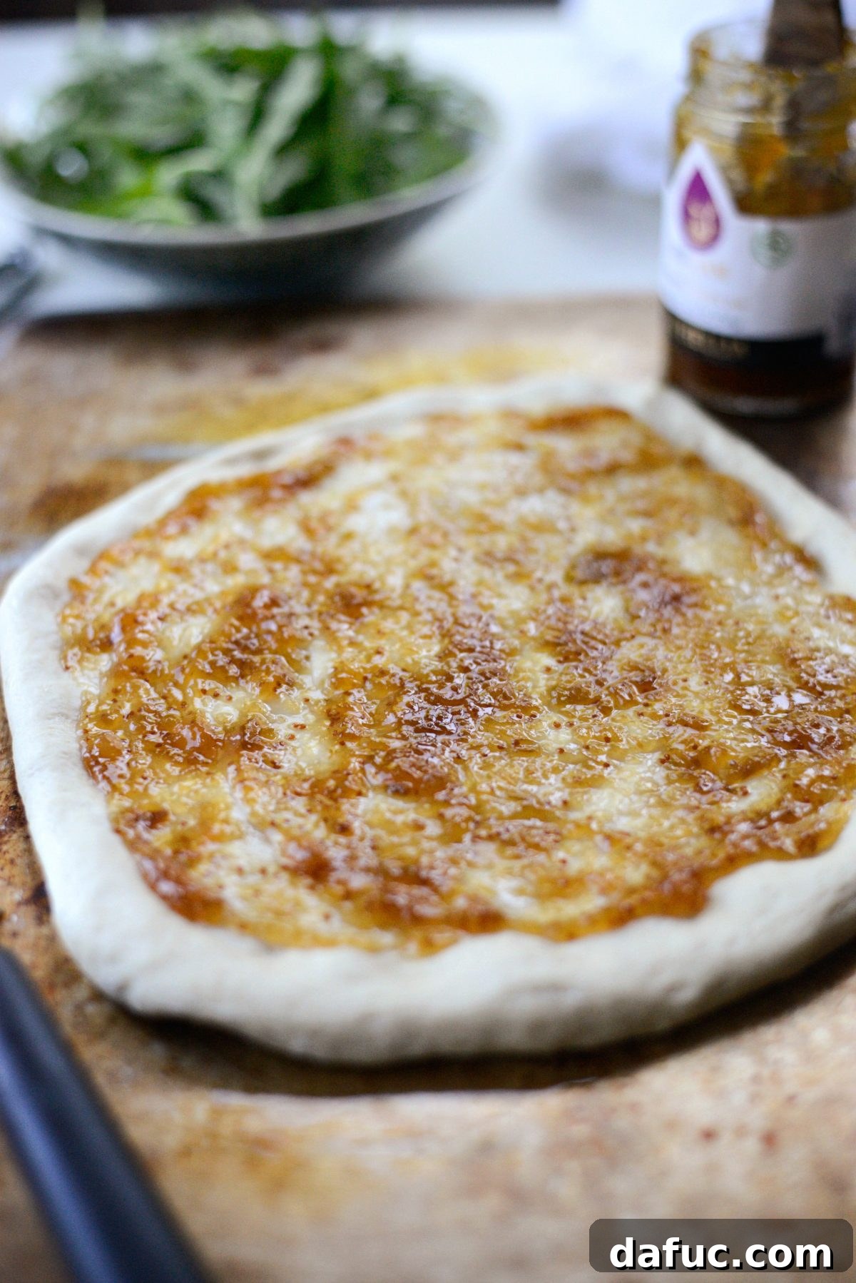 Thin layer of fig jam spread on pizza