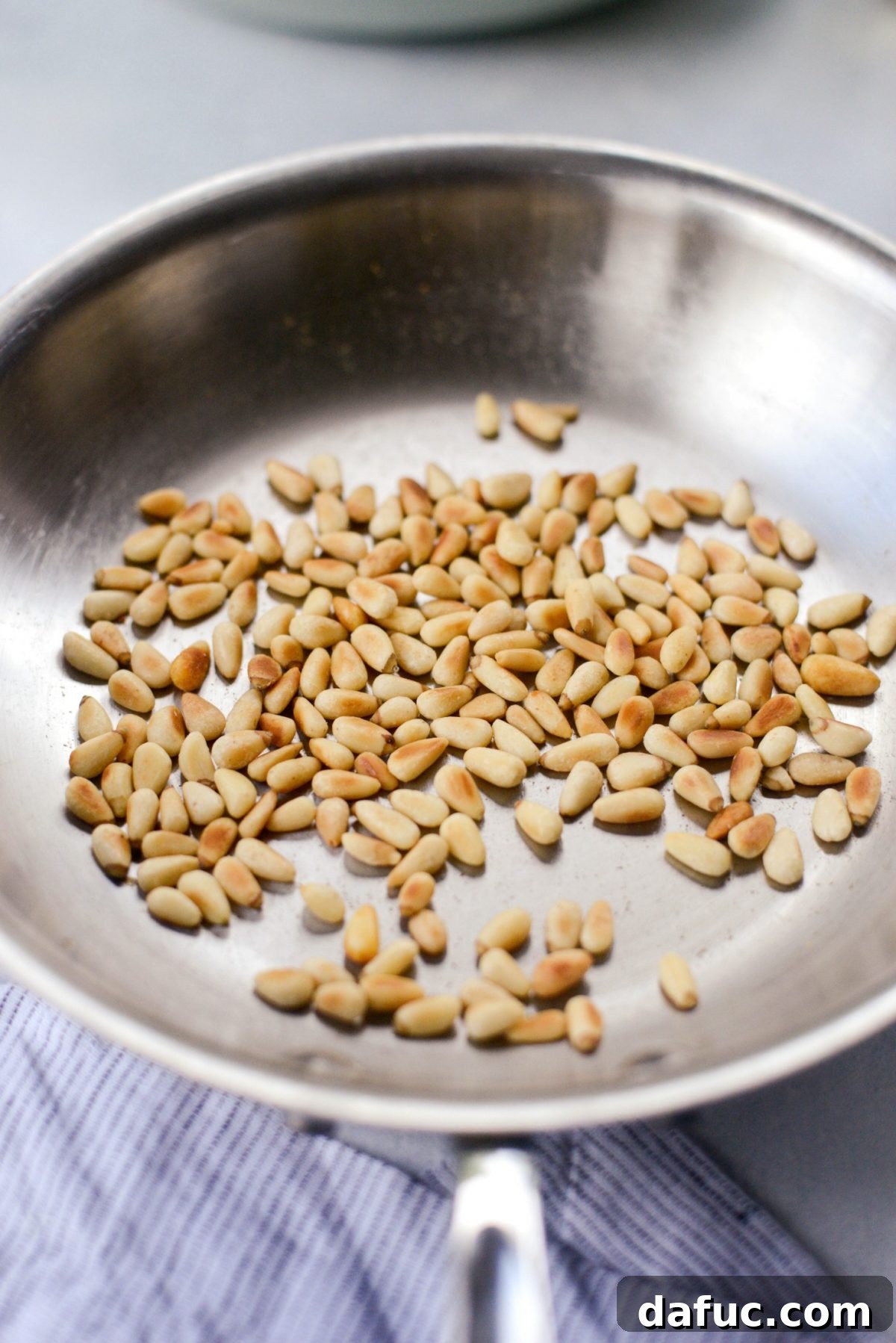 Shawarma Roasted Cauliflower & Chickpea Bowl 9 Pine nuts toasting in a dry skillet over a stove