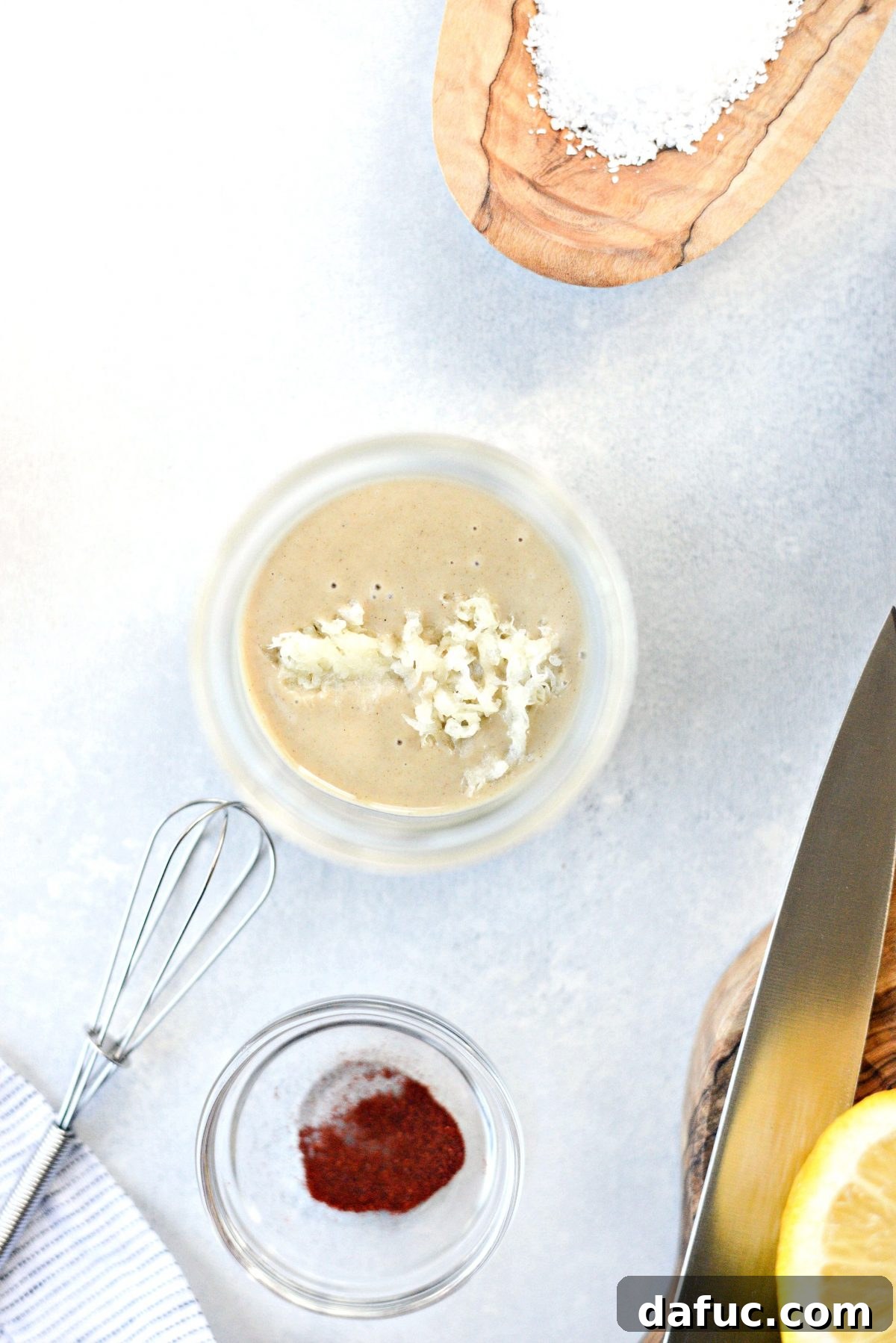 Zesty Lemon Tahini Dressing 5 Grated garlic being added to tahini in a bowl for the dressing