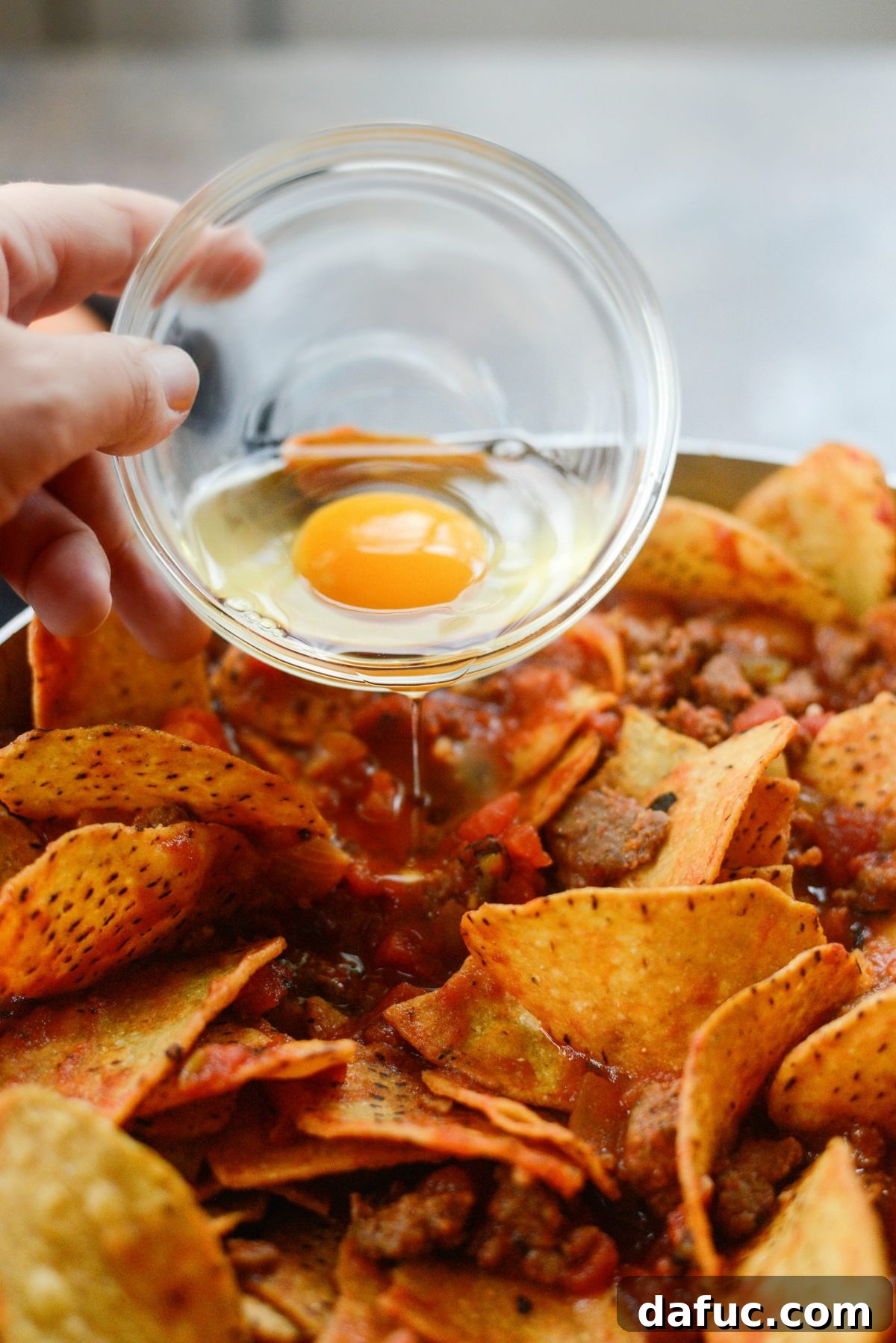 Hearty Chorizo and Sweet Potato Chilaquiles 14 Cracking eggs into wells in the chilaquiles mixture in the skillet